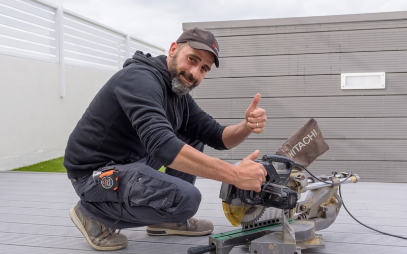 Chris parquet smiling at the camera with his thumb up, while installing parquet decking